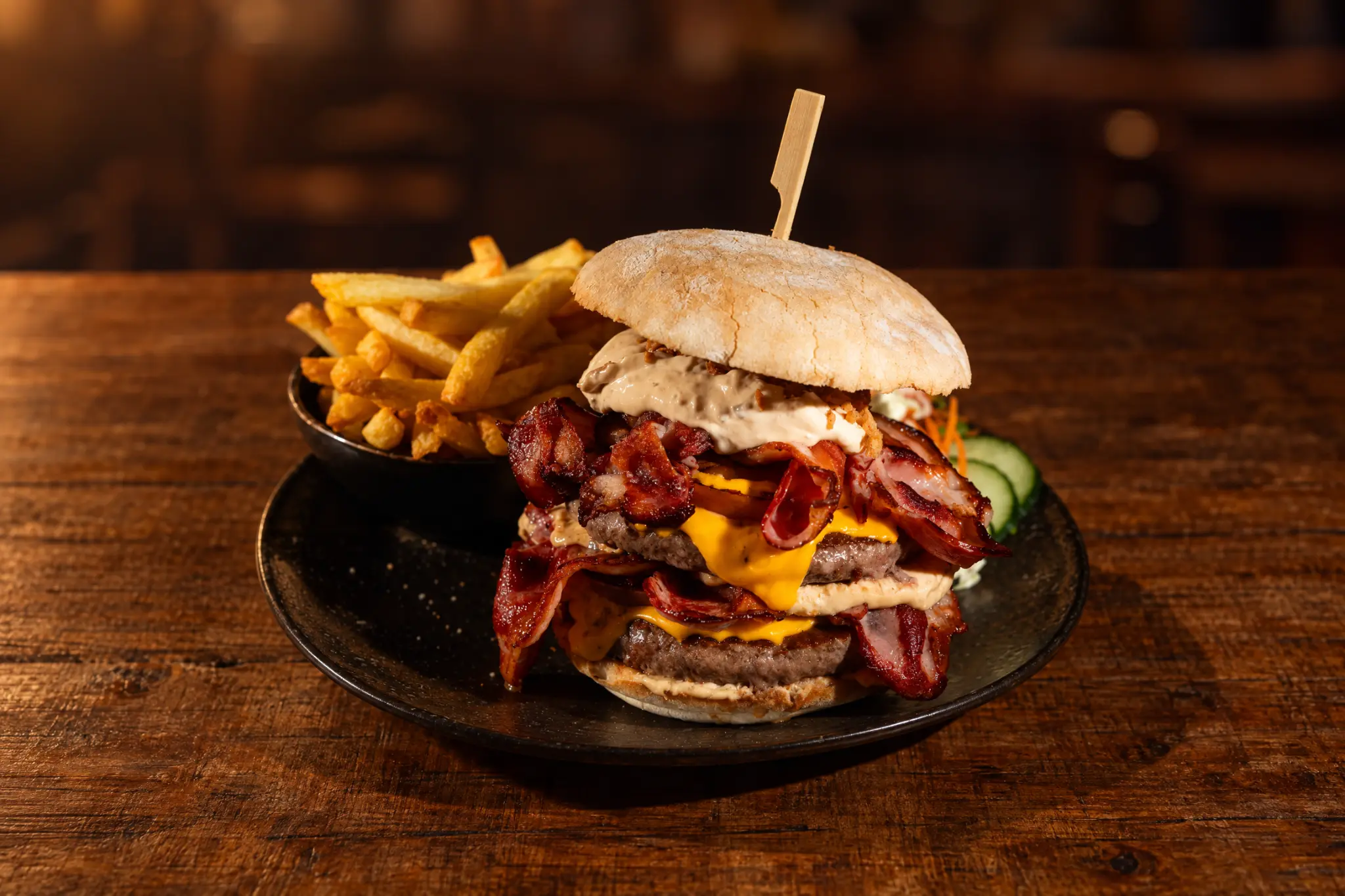 Double burger au bacon et cheddar, servi avec frites maison.
